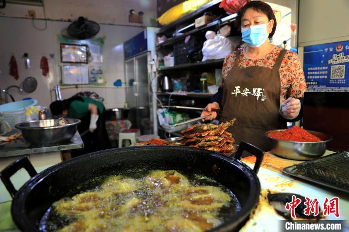 圖為平安驛·河湟民俗文化體驗(yàn)地內(nèi)的商戶炸干板魚?！⊙Φ?攝