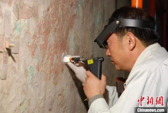 敦煌研究院研究員樊再軒進行壁畫修復。(資料圖)張云文 攝